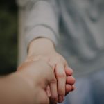 Hands holding in a gesture of connection and support, emphasizing unity and trust.