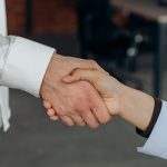 Close-up shot of two people's hands shaking, symbolizing partnership or agreement in an office setting.